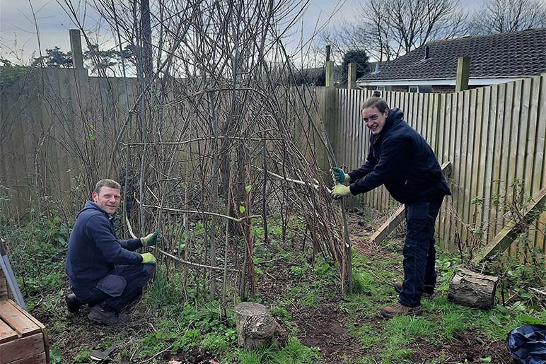 An apprentice and their supervisor constructing willow structures in the wildlife garden.