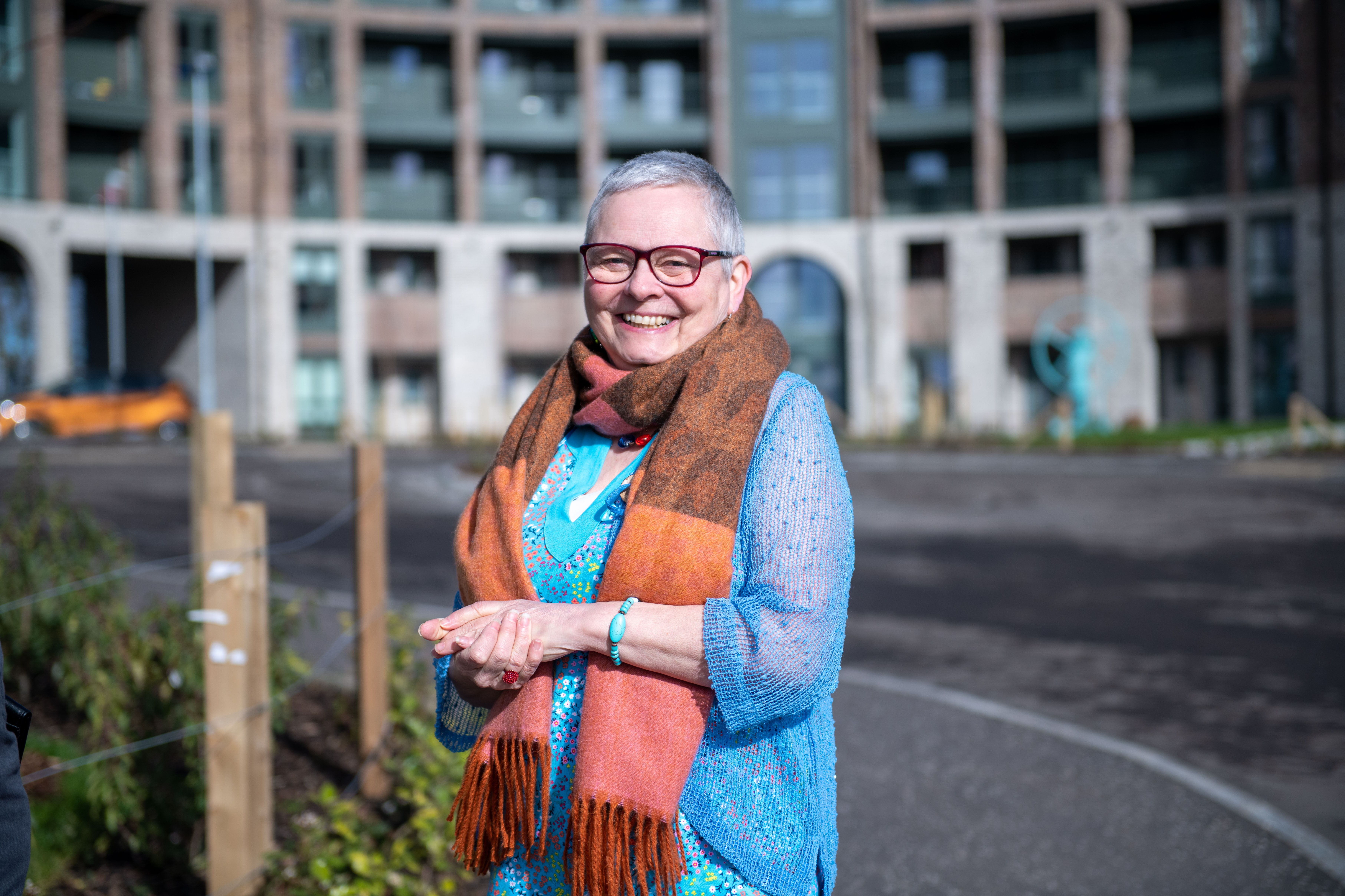 Frances Park A woman smiling in front of a block of flats