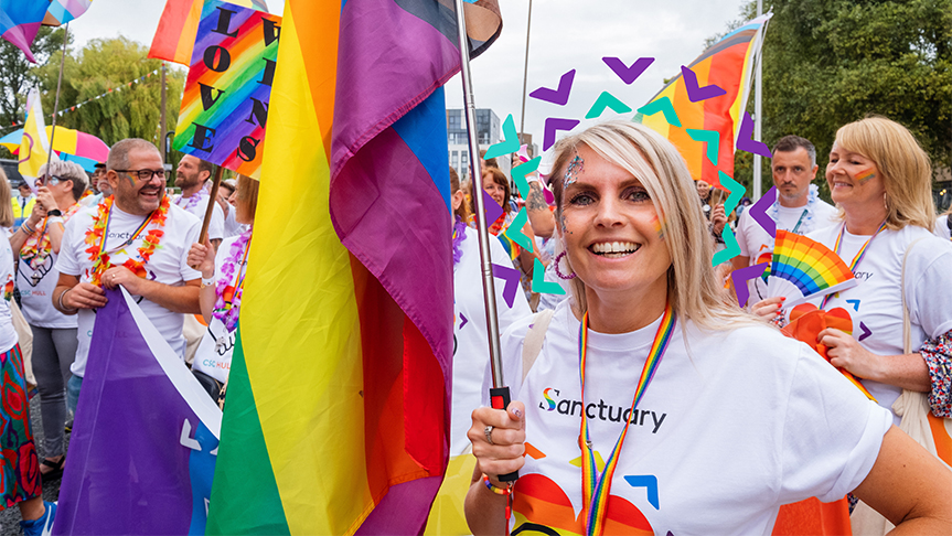 Sanctuary inclusion for all Sanctuary staff and residents wearing white shirts with rainbow hearts on carrying rainbow flags taking part in a march for a PRIDE event