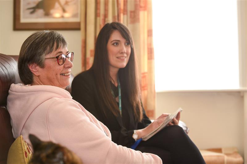 A Housing Officer and a resident sat on a sofa together in the residents home