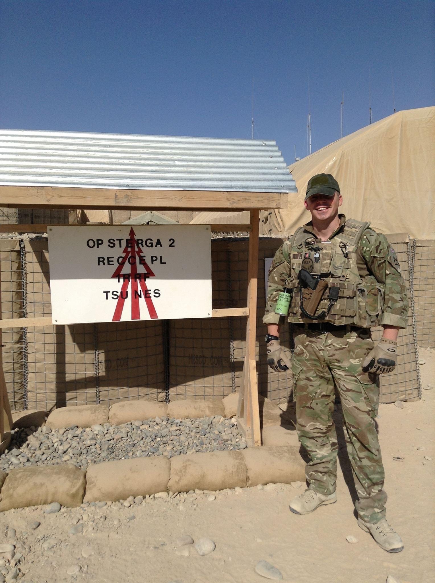 Chris stood in his military uniform in front of a sign in the dessert