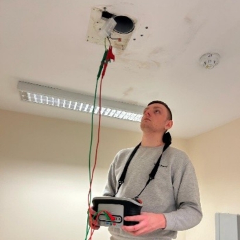 Image shows a man looking at the ceiling or a building and performing a safety test for some equipment