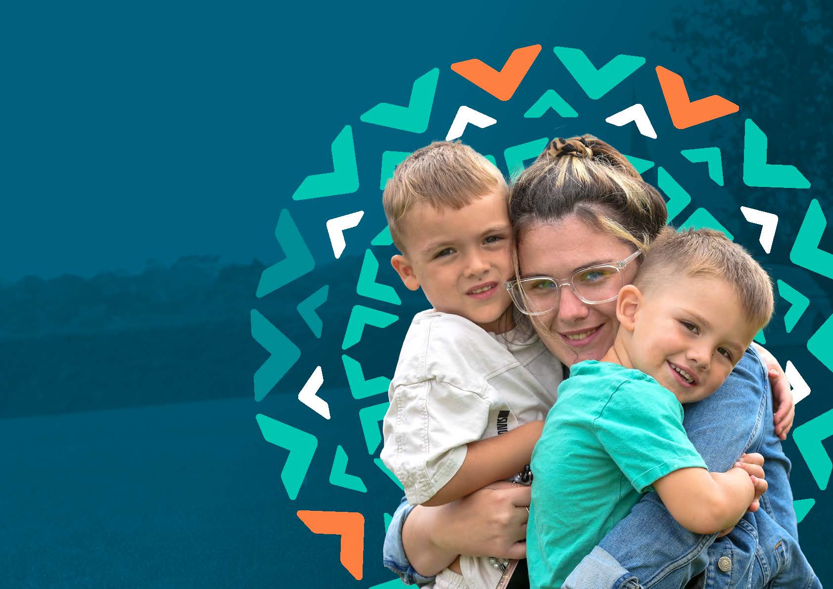 A young woman with glasses is smiling and hugging two young boys, one on each side