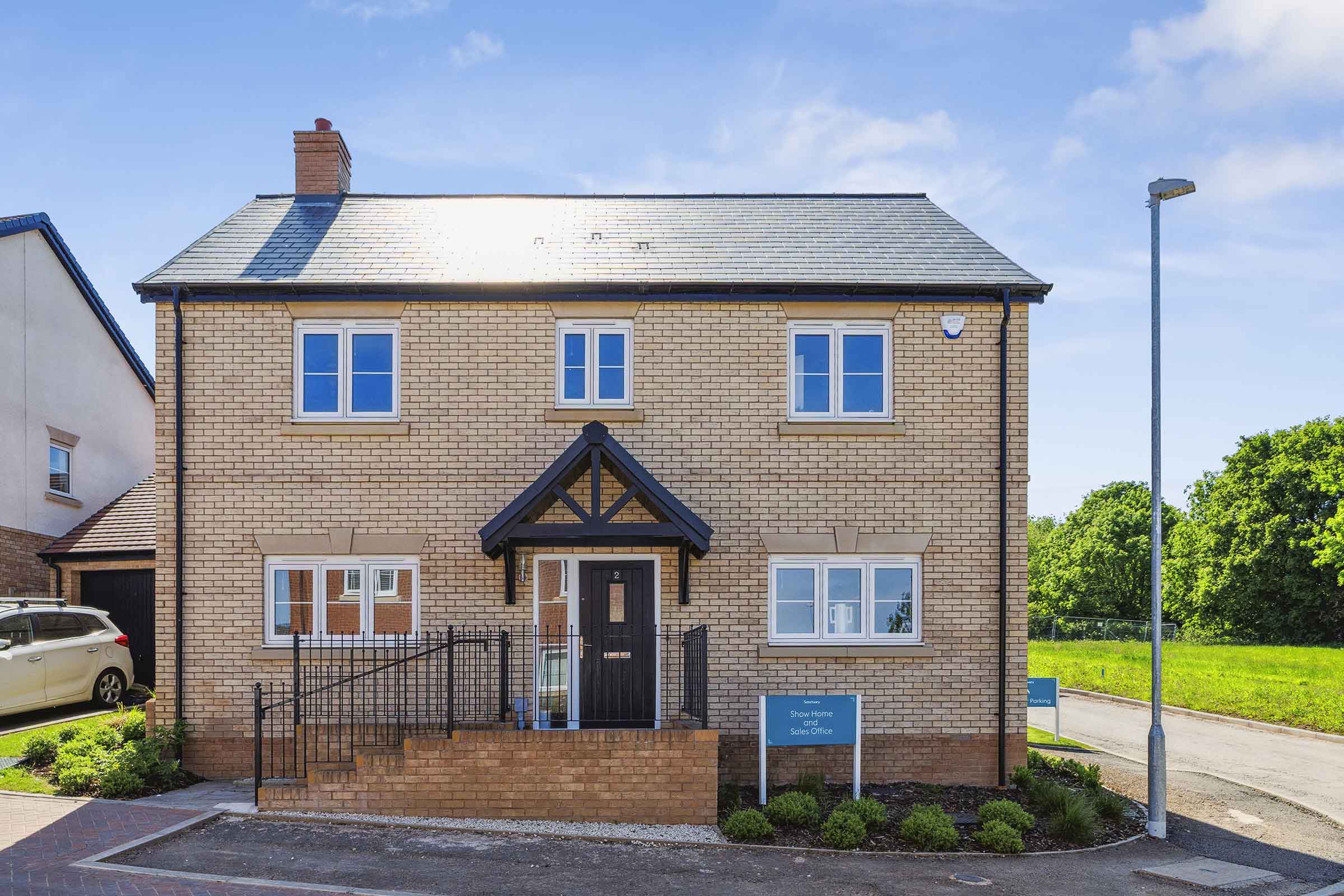 Front exterior of a two-story brick house with black front door and small landscaped area.