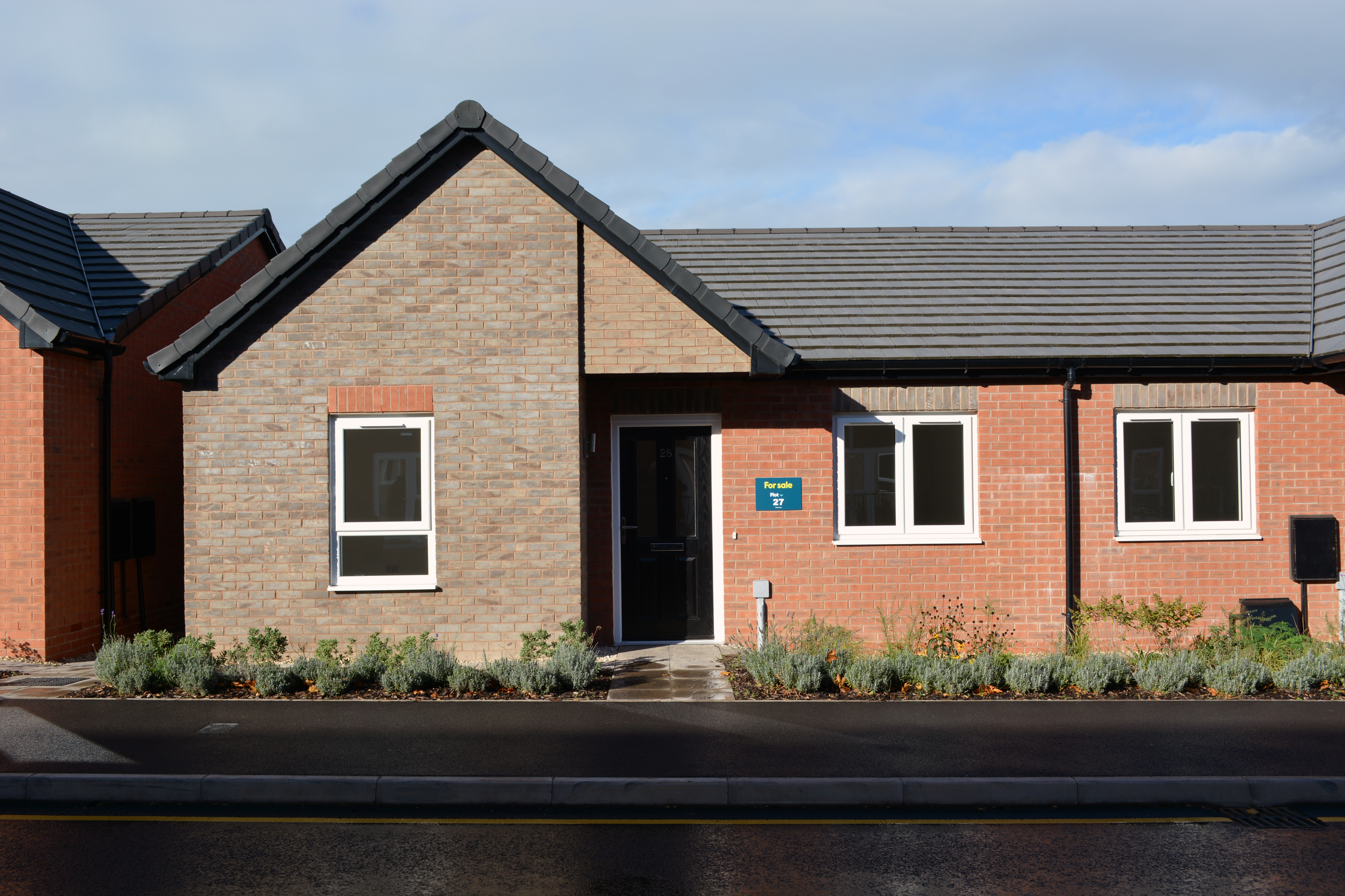 A grey brick semi-detached bungalow