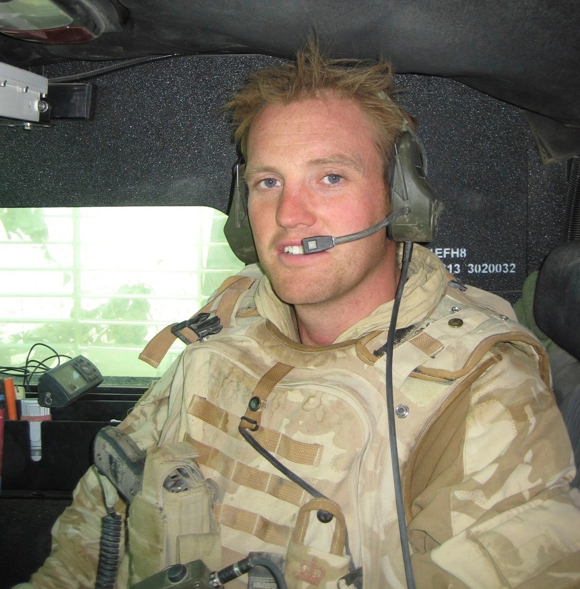 An archive photo of Tristram Channer during his time with the Armed Forces. He is wearing camouflage gear and a headset.