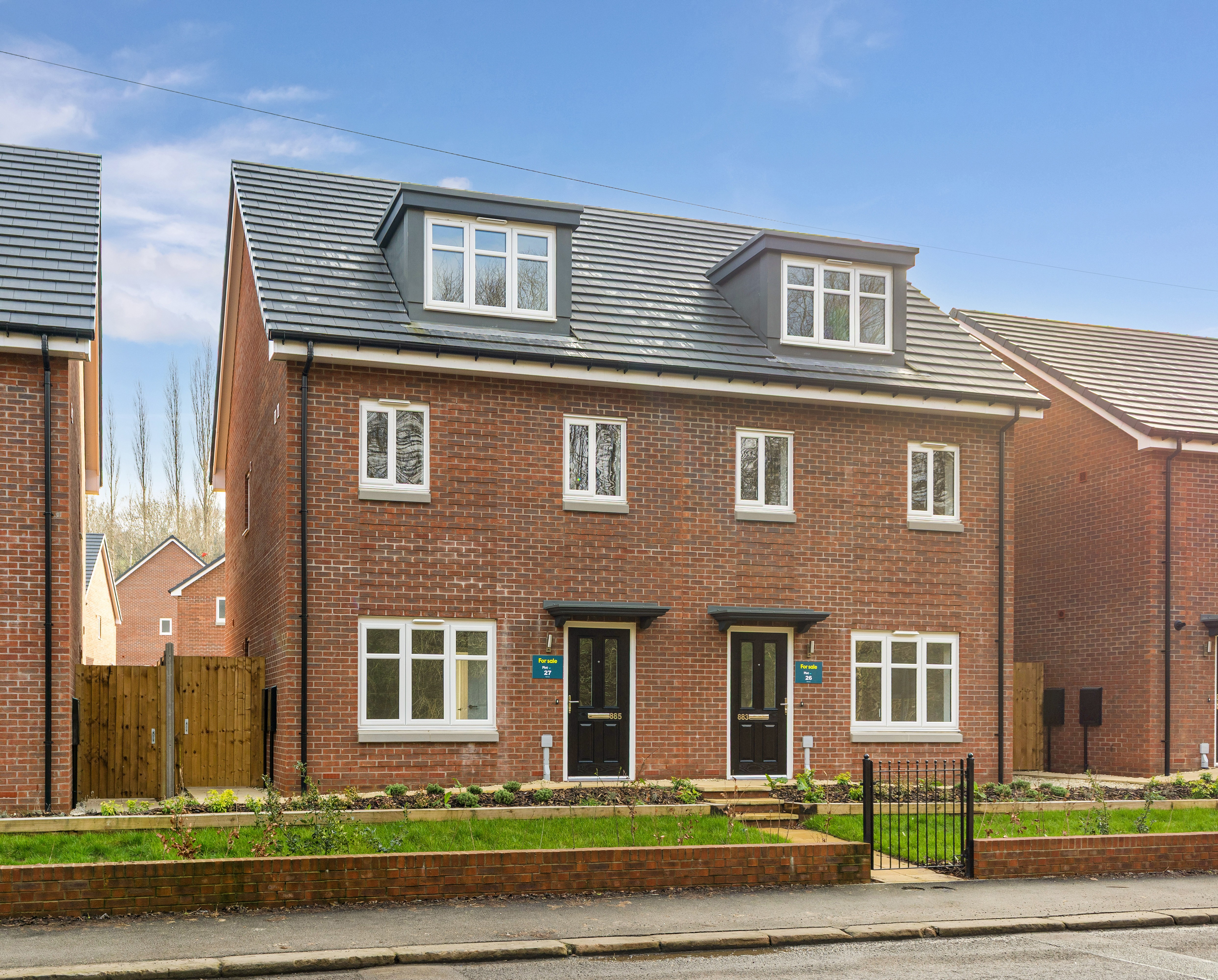 Front view of a red brick semi-detached house with white windows and a black front door.