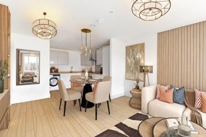 An open plan living room - kitchen area that is primarily coloured white and beige, it is sleek and fitted with white goods