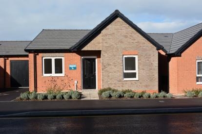 A grey brick semi-detached bungalow