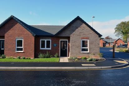 A grey brick semi detached bungalow