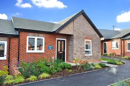 A grey brick semi-detached bungalow