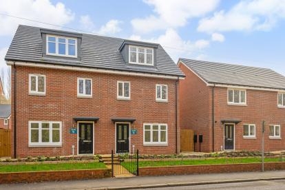Front view of a red brick semi-detached house with white windows and a black front door.