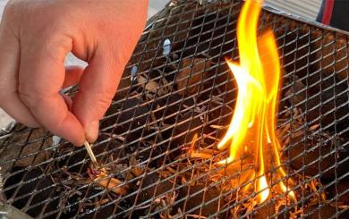 Somebody lighting a disposable barbecue with a match