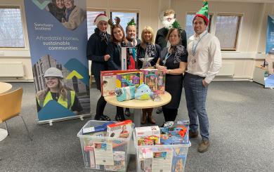 A group of people standing behind a selection of toys