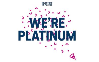 Graphic with the Investors in People logo at the top and bold text reading 'We’re Platinum' in dark blue, surrounded by pink confetti shapes on a white background.