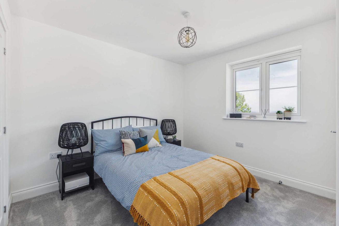 Spacious bedroom with double bed, two chests of drawers, and window