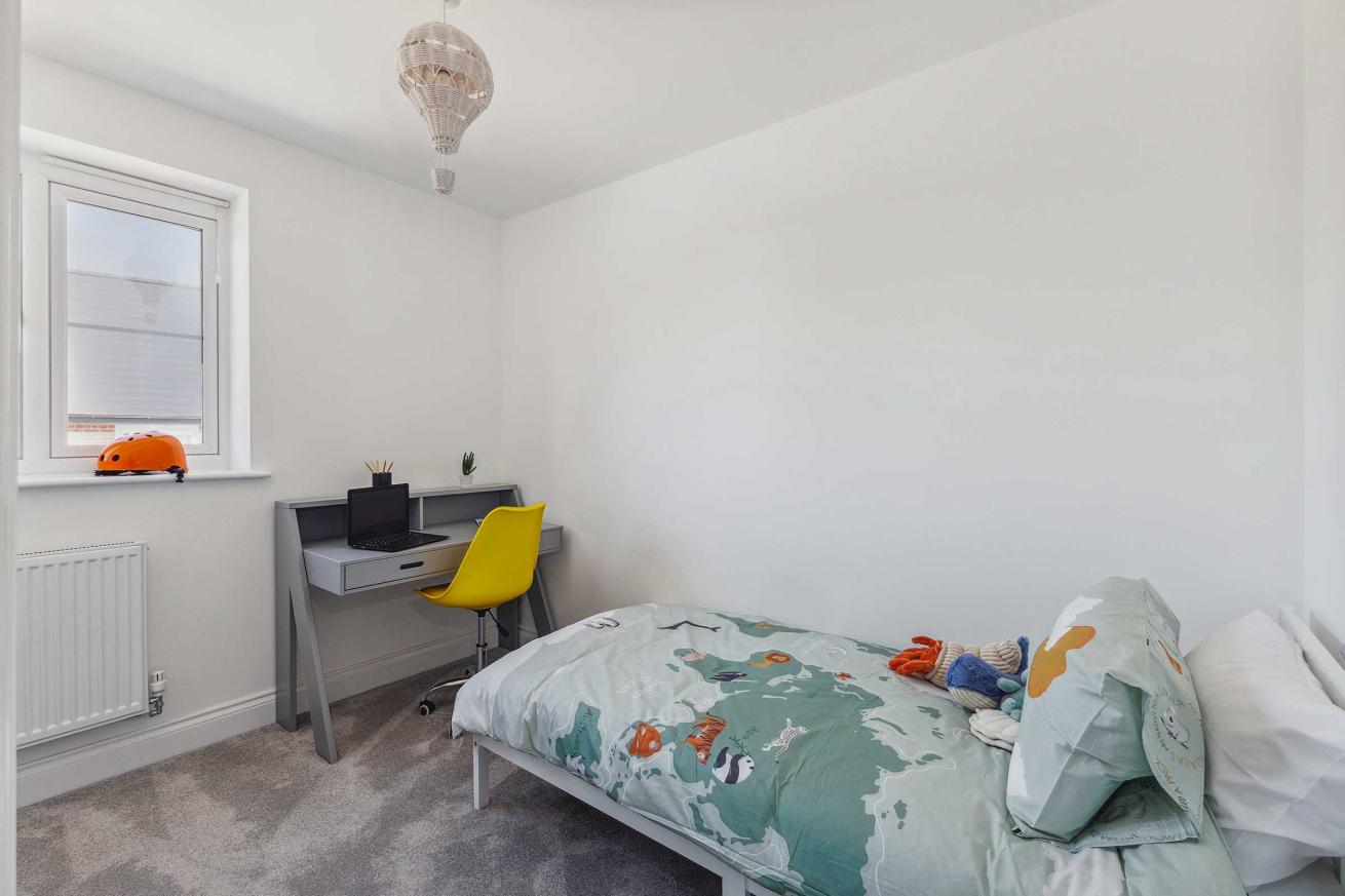  Small bedroom with single bed, desk, and window.