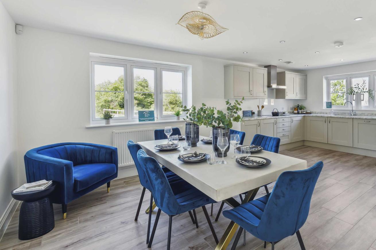 Dining area with table, six blue chairs, and open-plan kitchen.