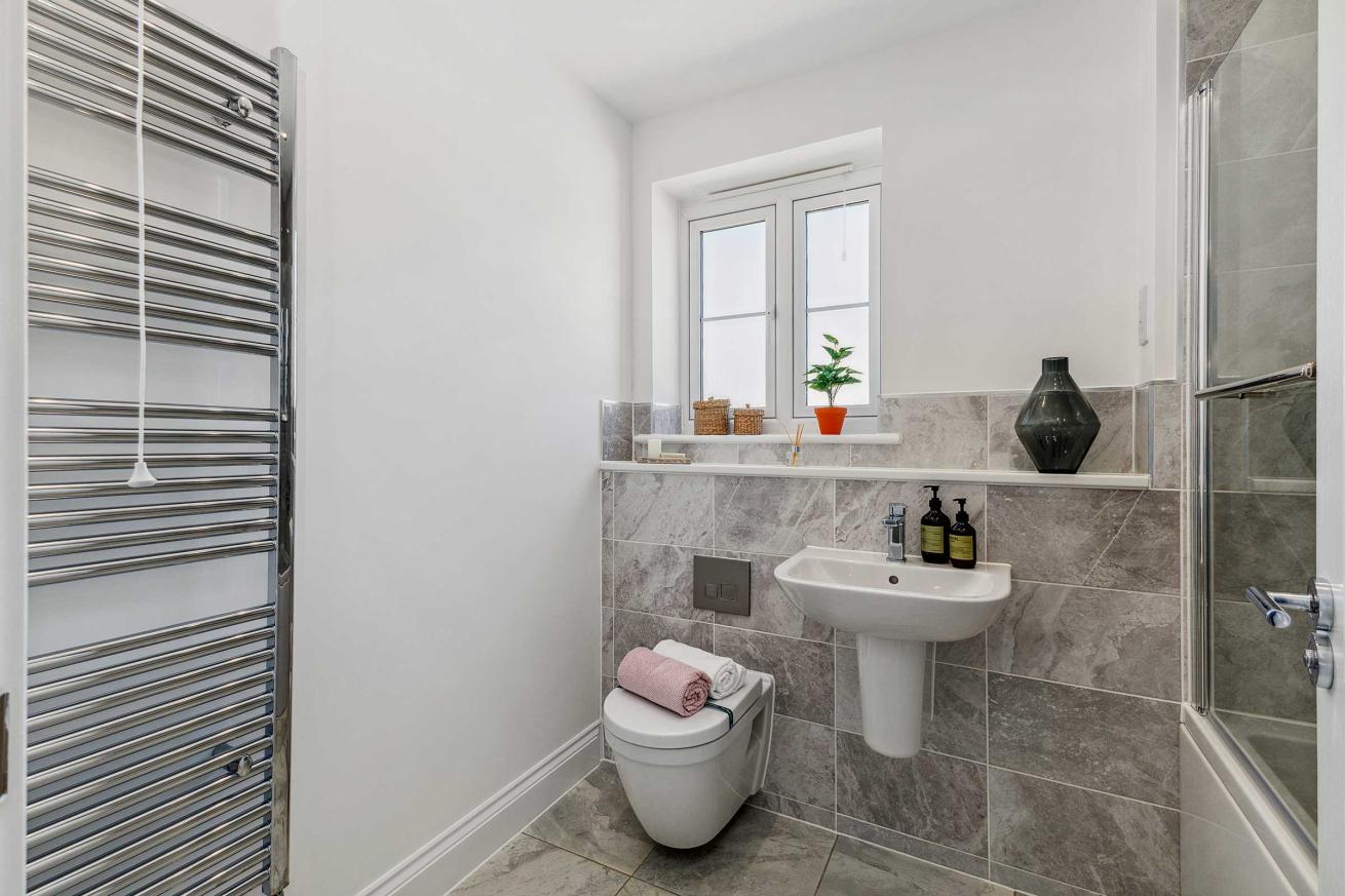 Bathroom with toilet, sink, towel rail, and tiled walls.