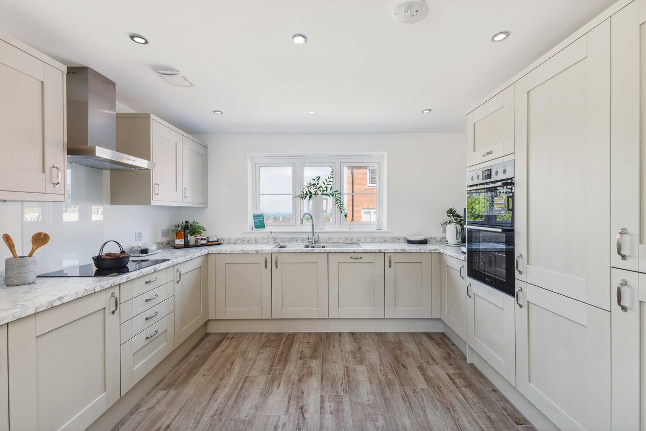  Modern kitchen with light cabinets, marble countertops, and window.