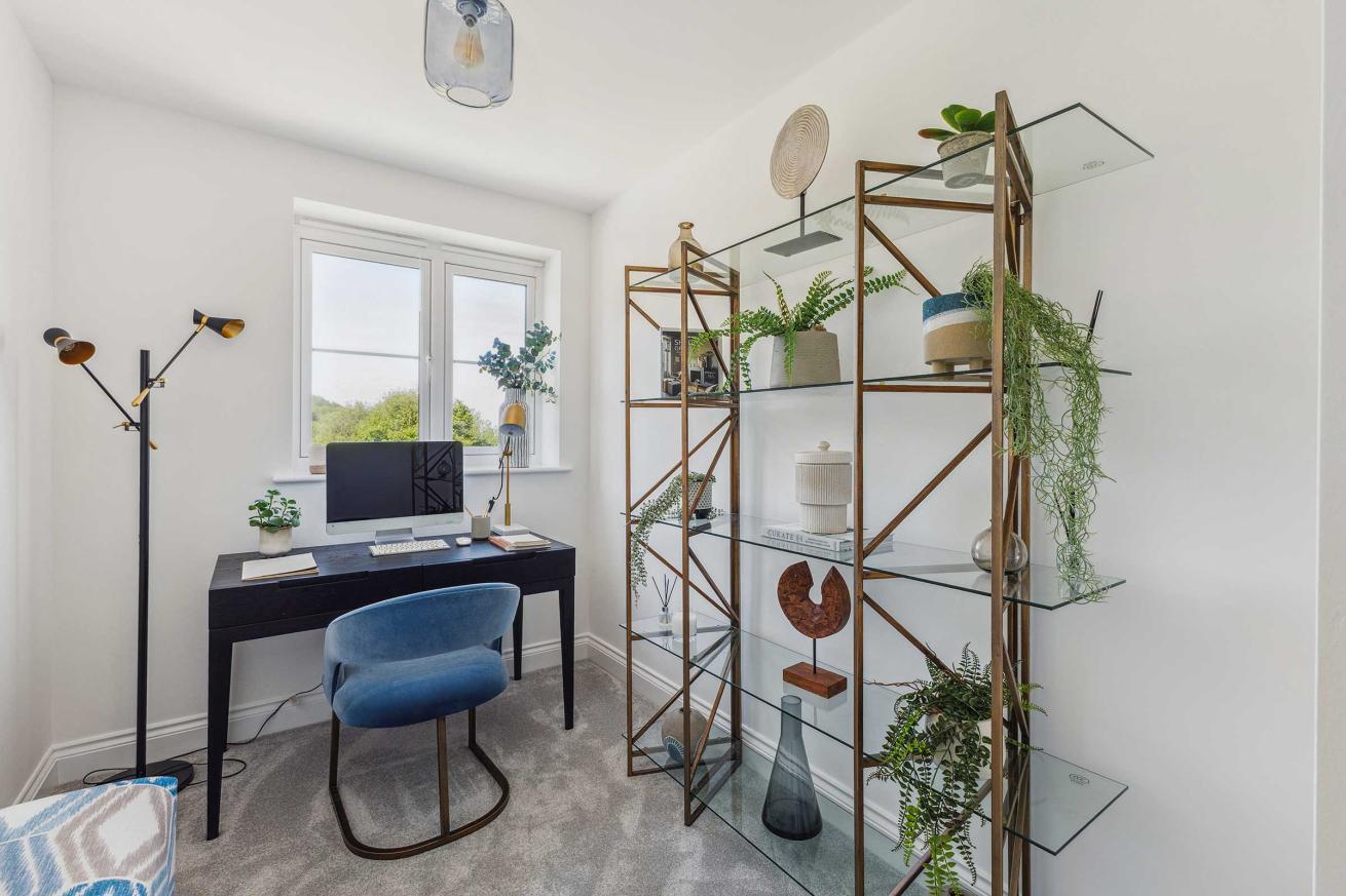 Study room with desk, chair, and shelving unit with decorative items.