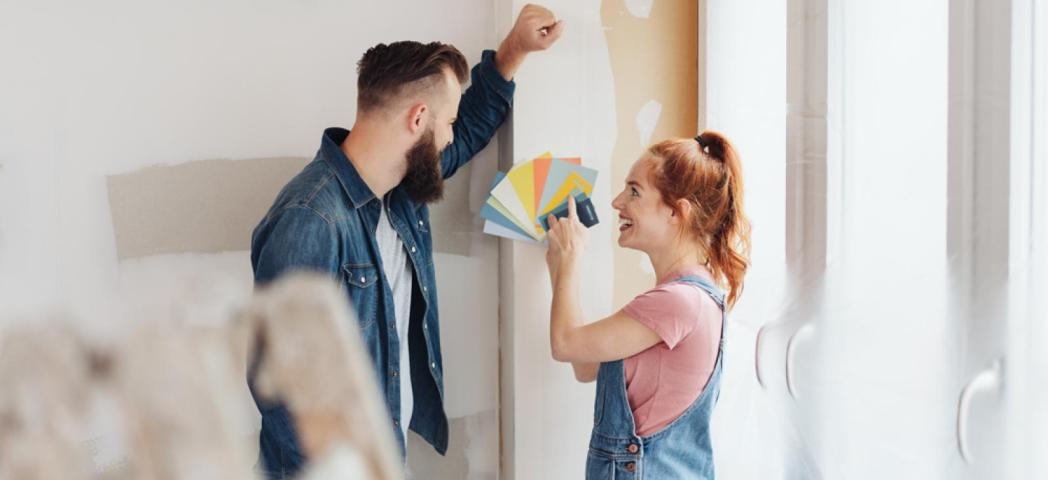 Two people looking at a colour swatch fan in front of a plain wall