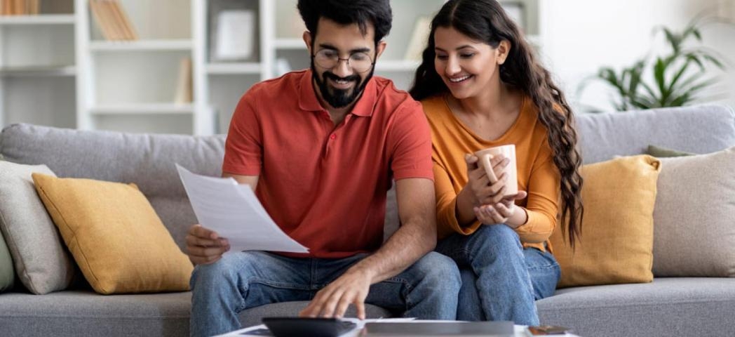 Two people sat on a sofa reading through some paperwork