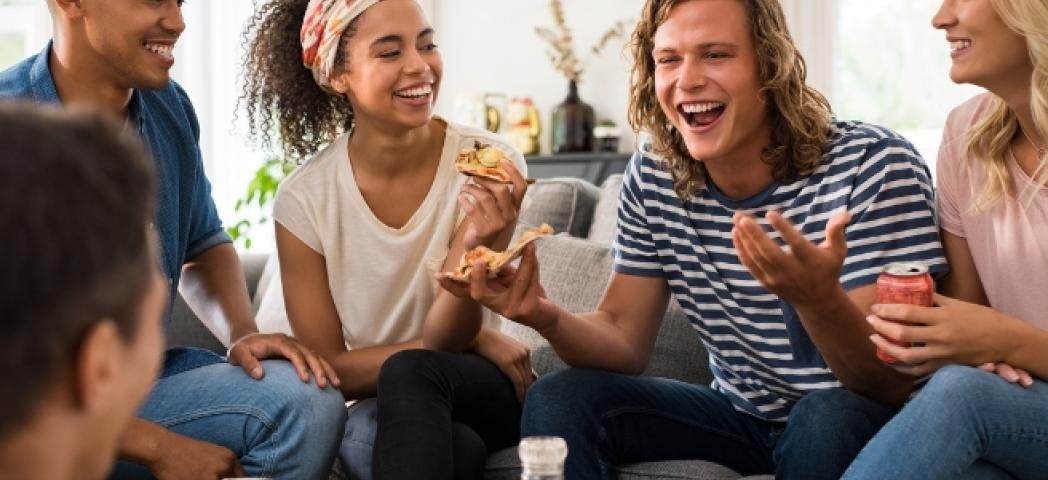 A group of friends laughing and eating pizza together