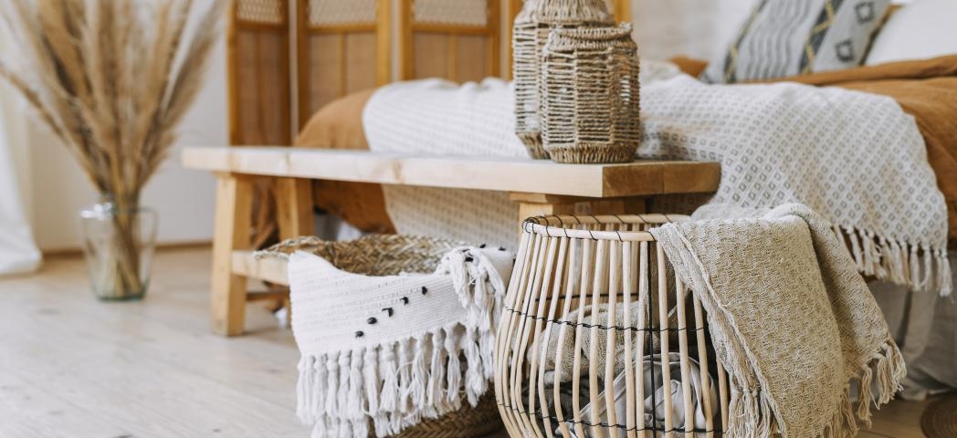 A cozy room featuring a bed, a wooden table, and a basket, creating a warm and inviting atmosphere.