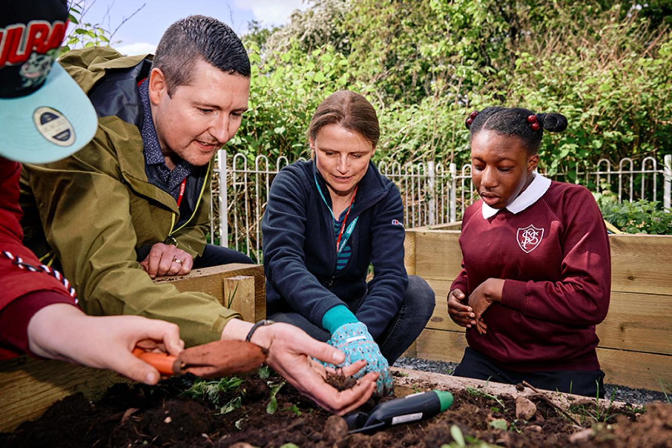 Working in the sensory garden An image showing people planting with a student.