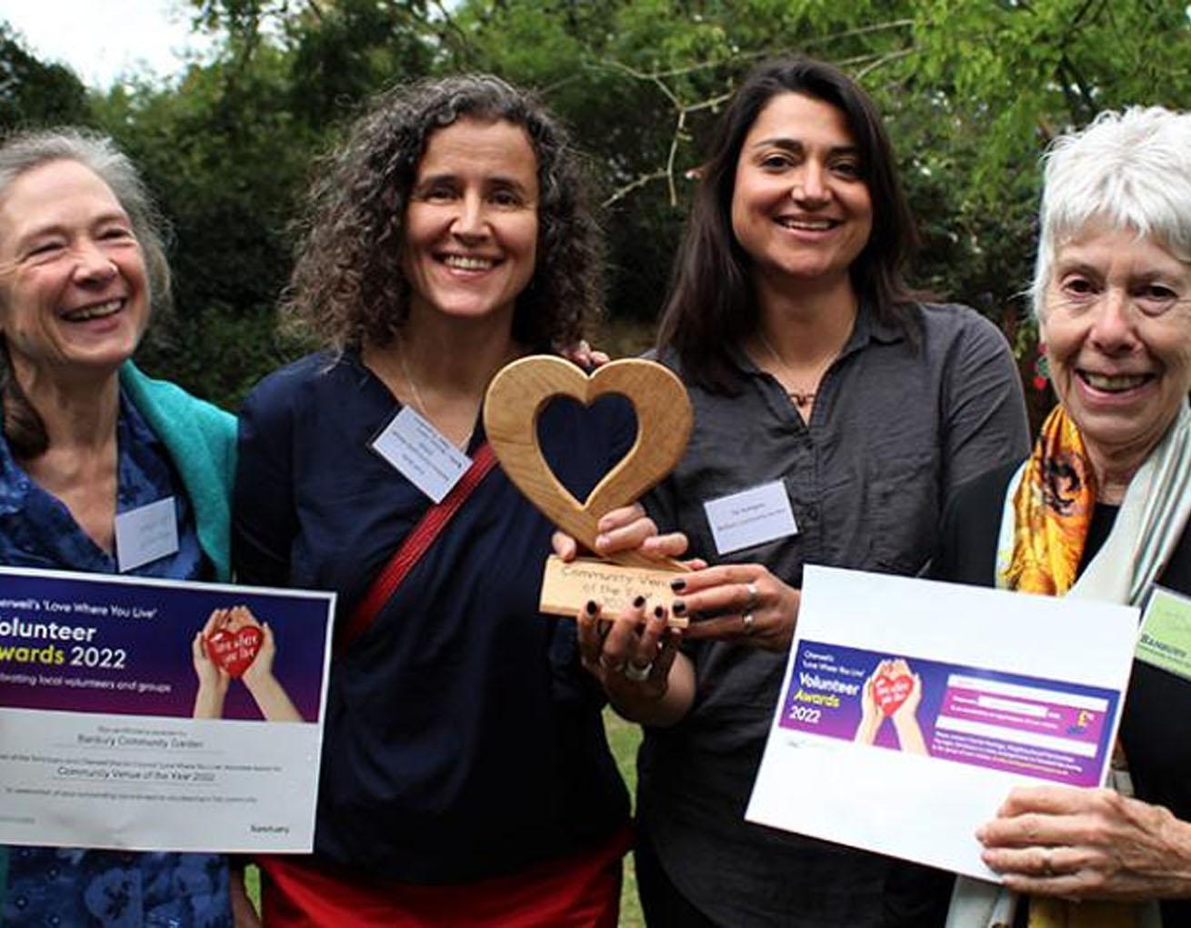 Four people holding awards