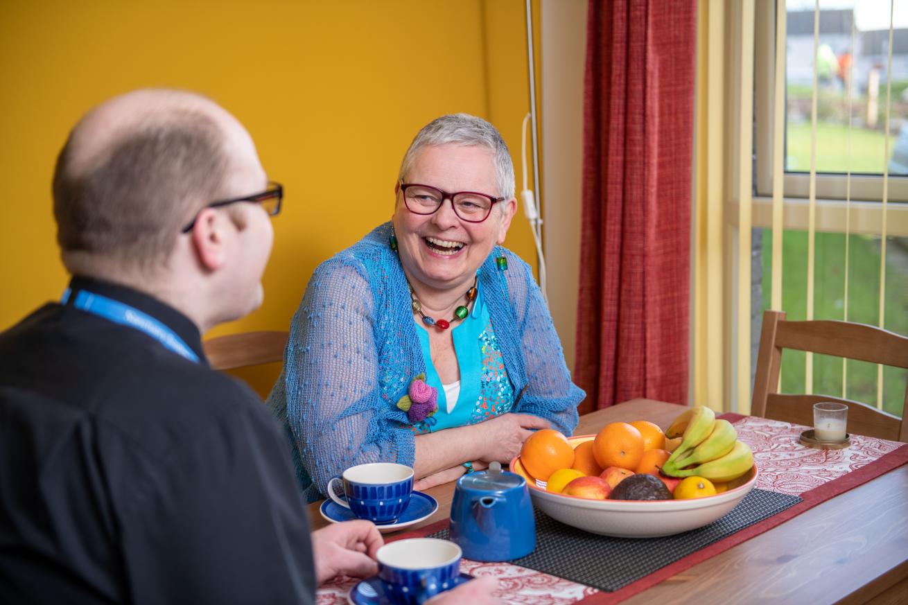 A man and a woman sitting at a kitchen table laughing