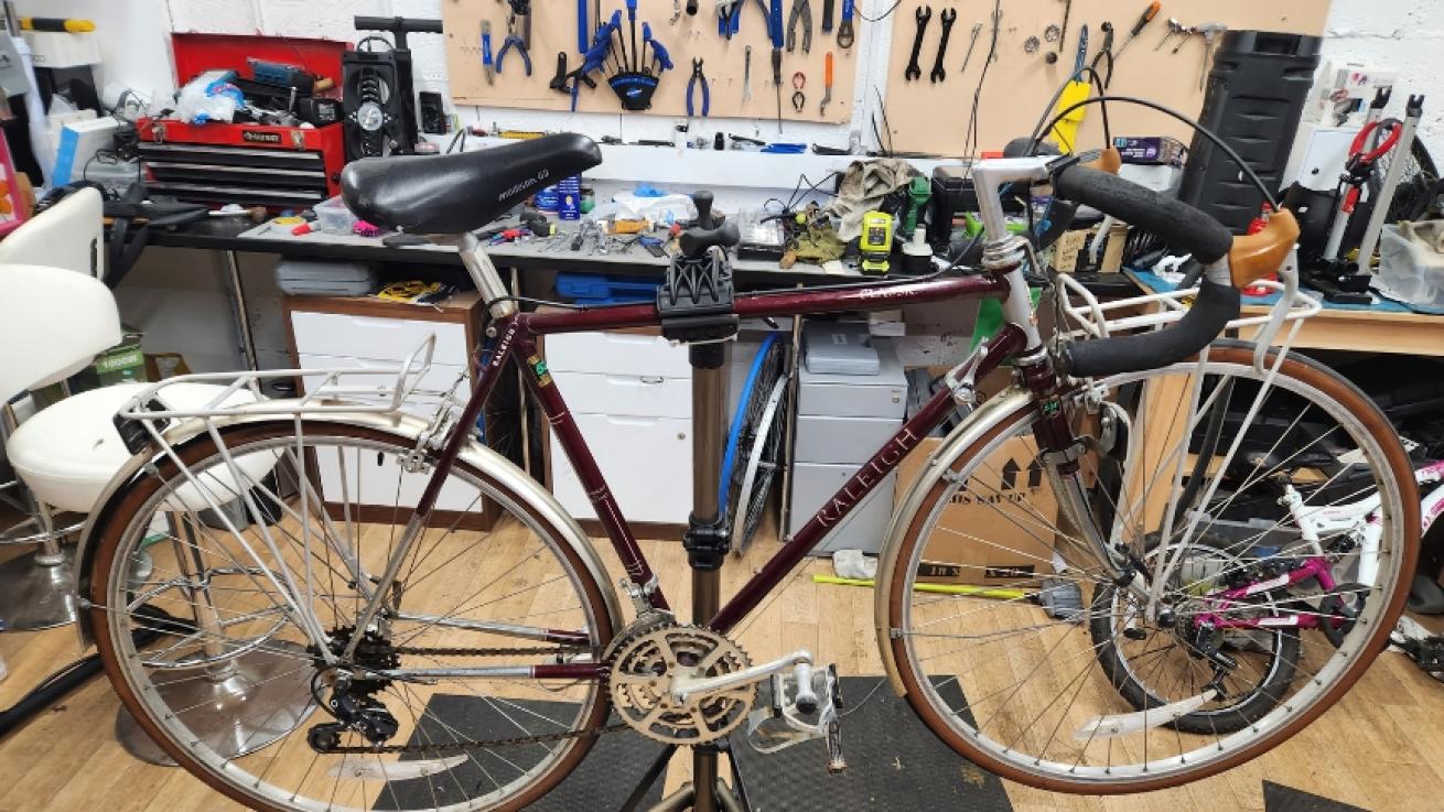 A bike that is suspended on a stand inside a workshop surrounded by tools