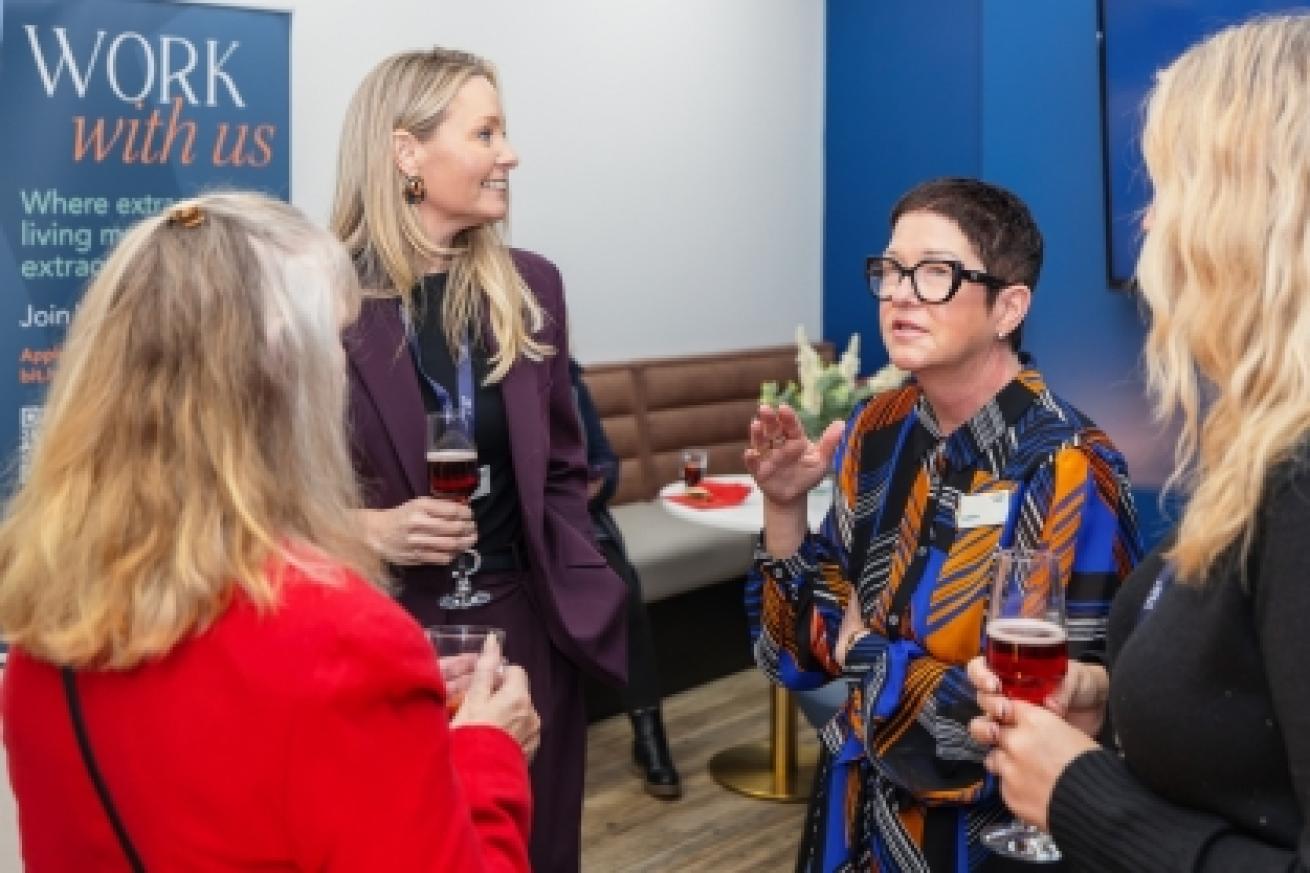 A group of four women are engaged in conversation at a social event. 