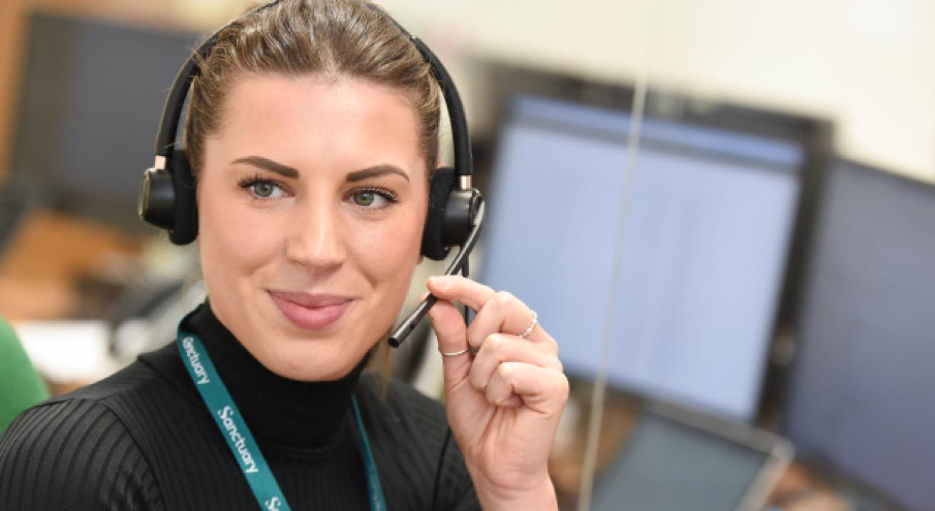 Sanctuary staff member wearing a headset at a desk, speaking into a microphone in an office environment.