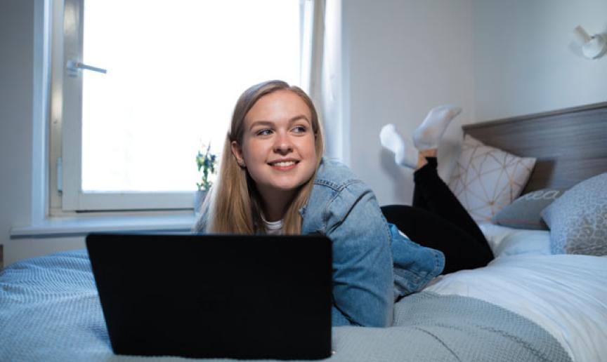 A student using their laptop in their bedroom
