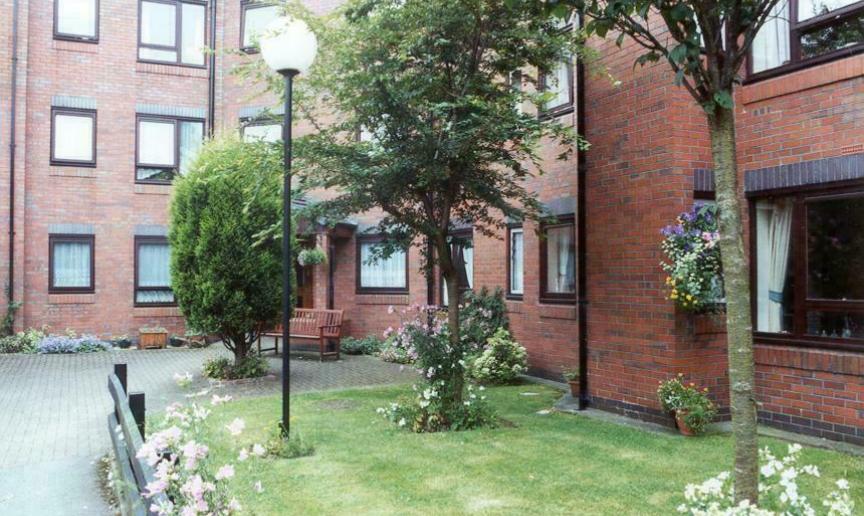 An apartment block with lush green trees outside