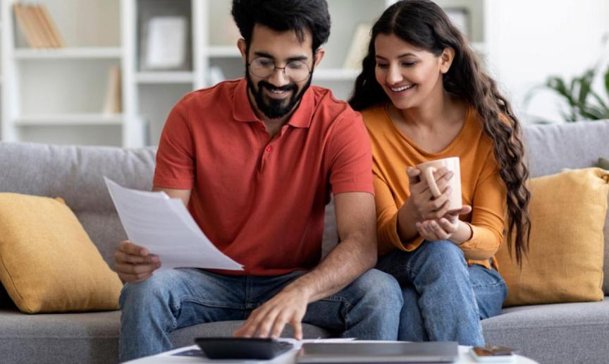 Two people sat on a sofa reading through some paperwork