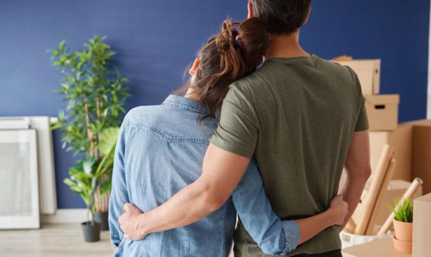 A couple embracing whilst looking towards some moving boxes