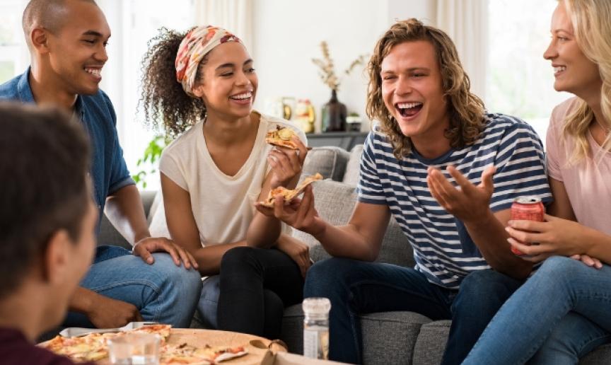 A group of friends laughing and eating pizza together