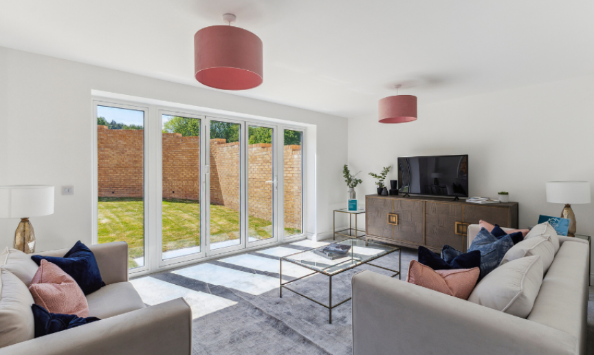 A new-build living room with white walls, patio doors leading to a sunny garden and stylish furniture inside
