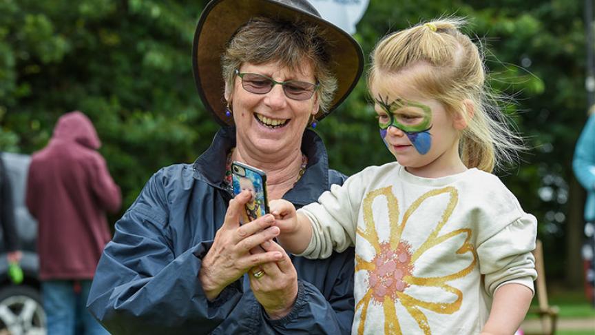 A woman showing her grandchild something on her phone during a community event. A woman showing her grandchild something on her phone during a community event.