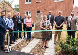 Cllr Jean Innes, joined by other borough and parish councillors, as well as Sanctuary and partner staff, cuts the ribbon on the site