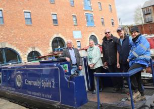 Five people standing on a moored boat smiling