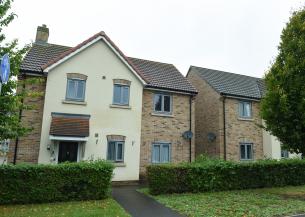 Two modern semi‑detached houses with cream and brick walls, grey windows, hedges and a footpath in front.