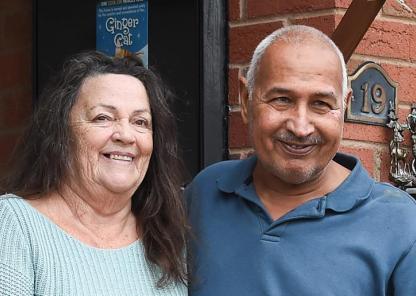 Two people smiling outside the front door of a house